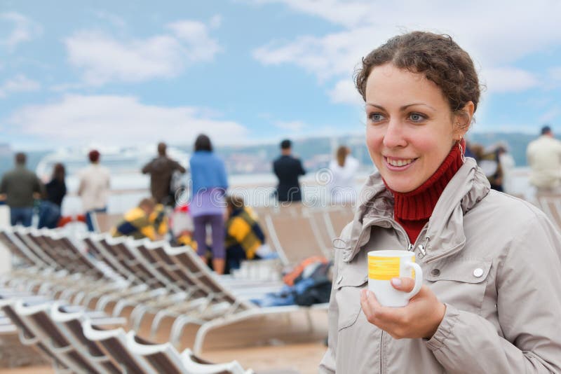 Girl holding cup on deck of big ship