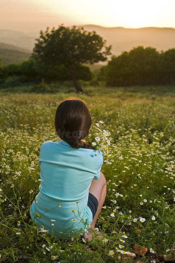 Girl holding flowers in field at sunset