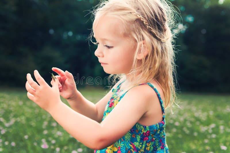 Girl holding grasshopper, curiosity and education concept. Adorable young girl holding grasshopper, curiosity and education concept royalty free stock image Girl holding grasshopper, curiosity and education concept. Adorable young girl holding grasshopper, curiosity and education concept royalty free stock image