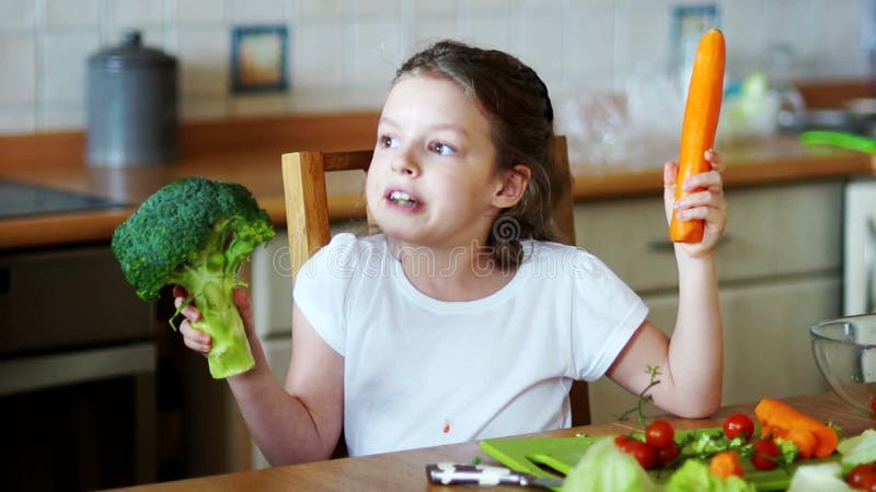 Girl holding in the hands of broccoli and carrots.