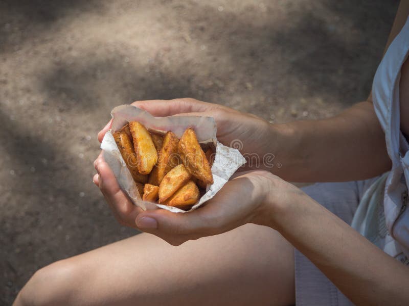 A girl holding a pack of fries in hand in the street. Small pack of potato fries, fast snack royalty free stock photography A girl holding a pack of fries in hand in the street. Small pack of potato fries, fast snack royalty free stock photography