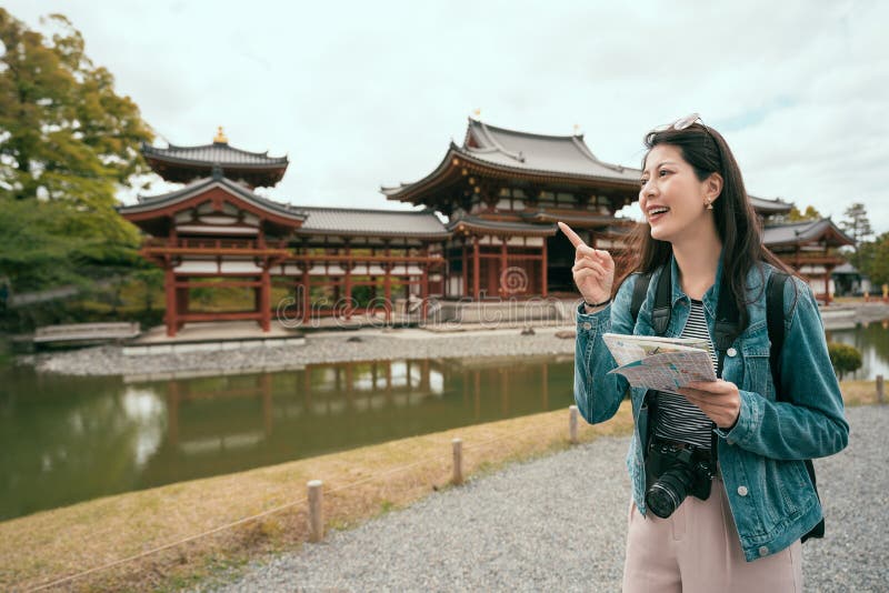 Girl holding paper map cheerfully pointing sky royalty free stock photo