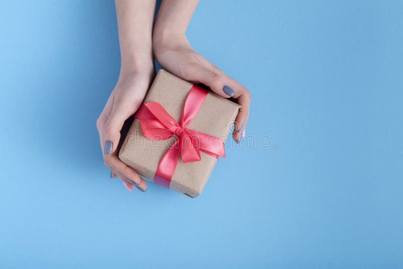 Girl holding a present in hands, women with gift box with a tied red ribbon...