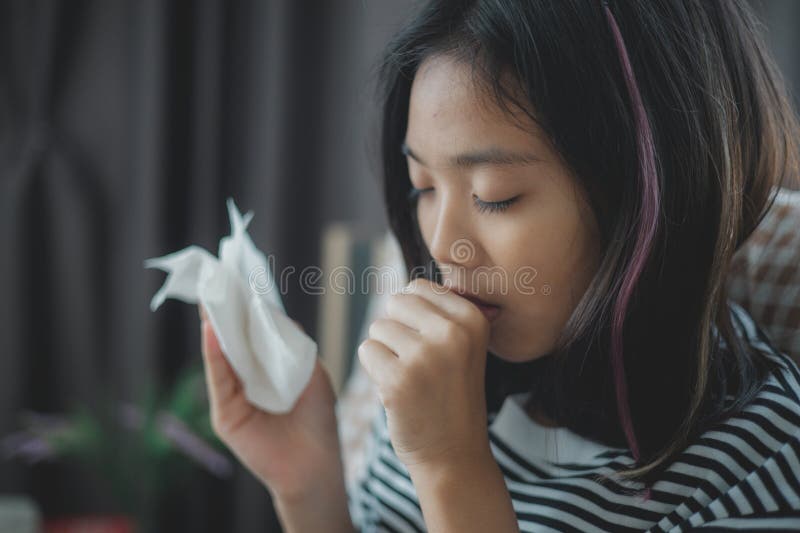 A girl is holding a tissue and coughing stock photography