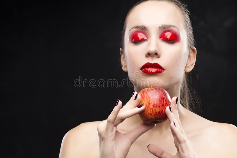 Girl holds apple with the red eyeshadow covered with gloss