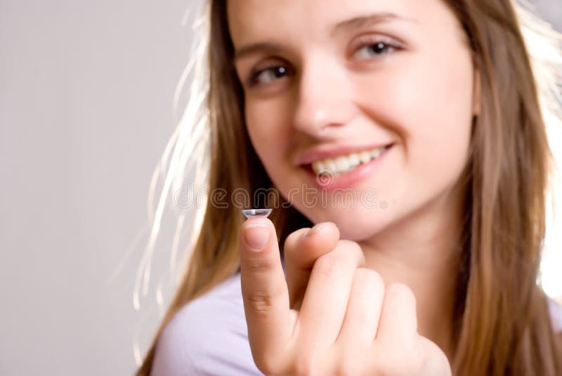 A girl holds a contact lens