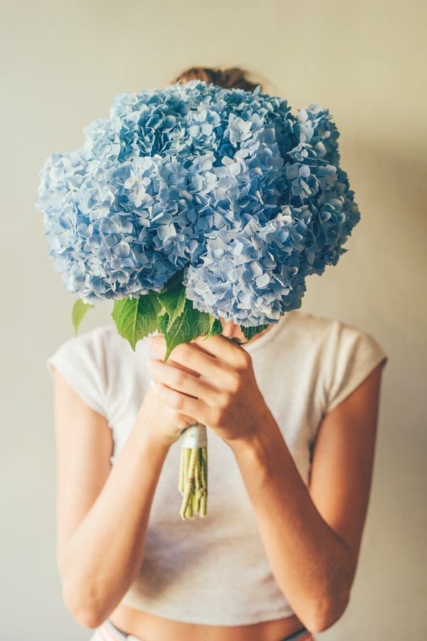 Girl holds in front of her a lush bouquet of blue hydrangea