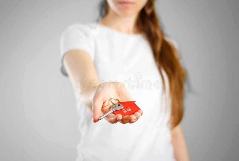 A girl holds the keys to the house. Key ring red house.