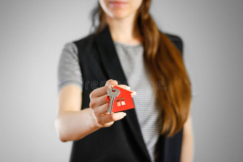 A girl holds the keys to the house. Key ring red house.