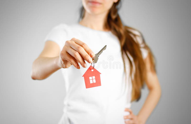 A girl holds the keys to the house. Key ring red house.