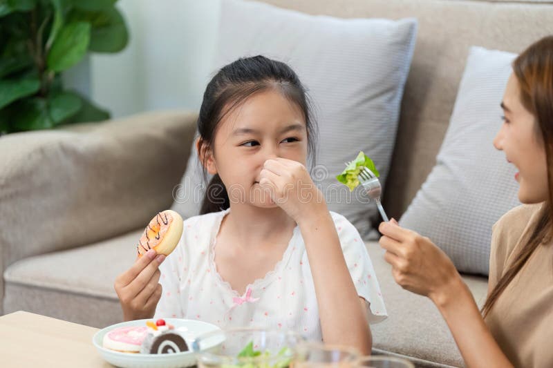 Wellness eating: girl reacting to salad with a cookie in hand stock image