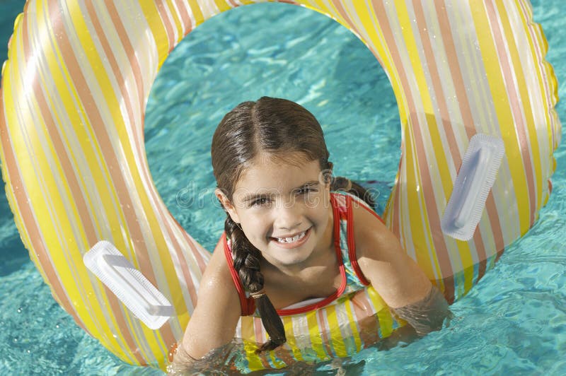 Portrait of a cute elementary girl with inflatable ring in swimming pool
