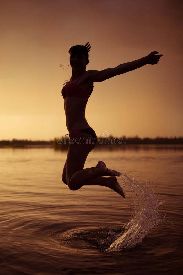 Girl jump in river at sunset