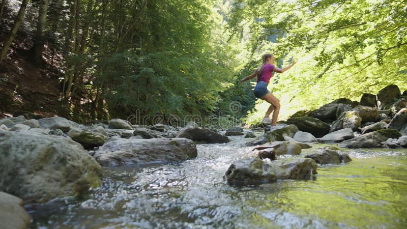 Girl jumping over pristine creek in the woods