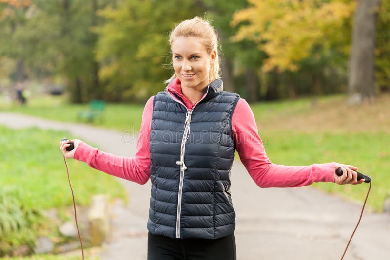 Fit smiling girl jumping rope in park