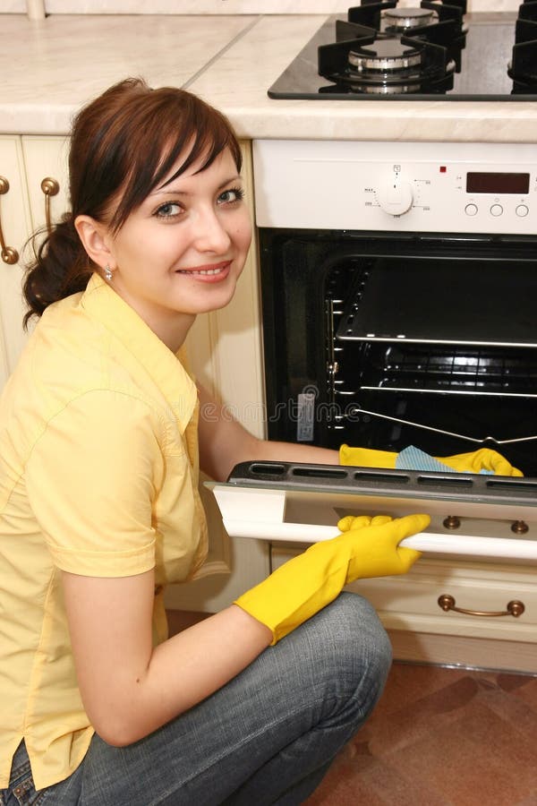 The girl on kitchen wipes an oven