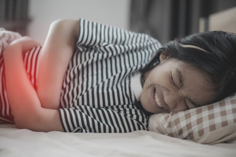 A girl is laying on a bed with a stomach ache royalty free stock photo
