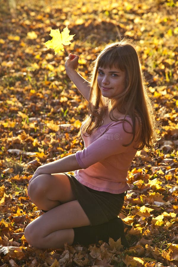 Girl with leaf of maple in sunlight