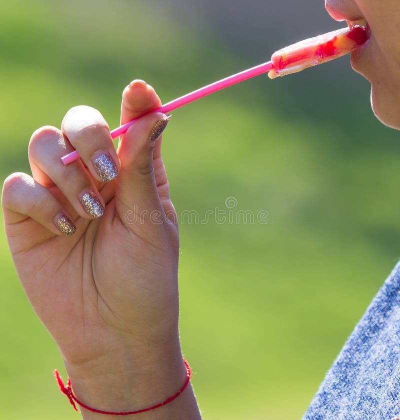 Girl licks a sweet candy mouth on nature royalty free stock photo Girl licks a sweet candy mouth on nature royalty free stock photo