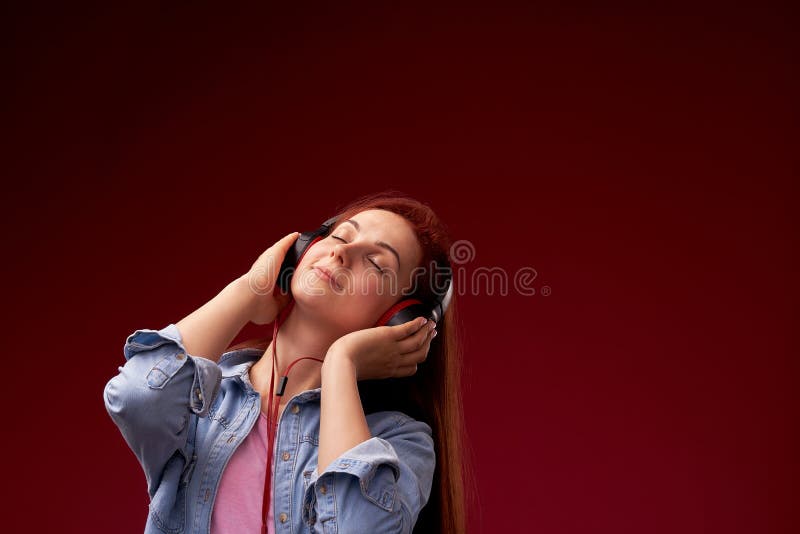Girl listening to music in headphones . red-haired young beautiful girl in jeans and t-shirt happy smiling in headphones, royalty free stock photography Girl listening to music in headphones . red-haired young beautiful girl in jeans and t-shirt happy smiling in headphones, royalty free stock photography