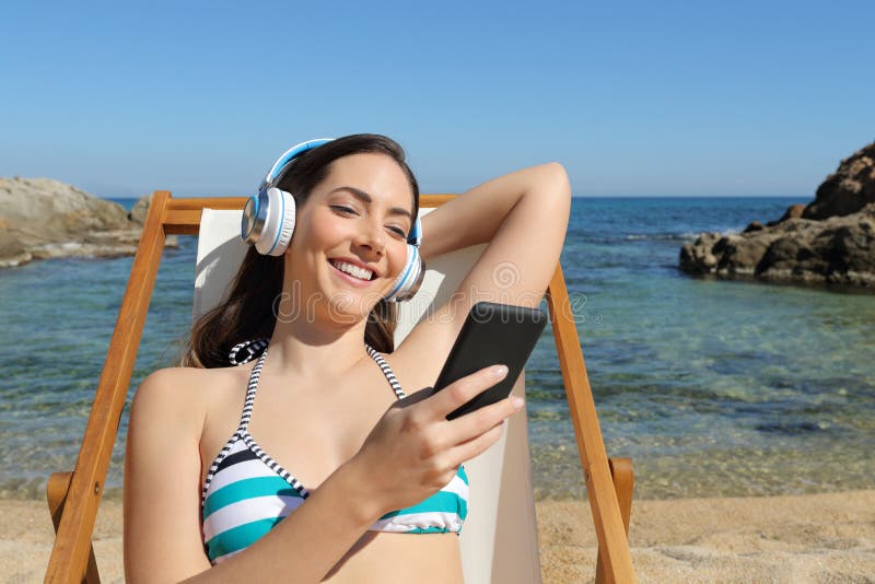 Girl listens to music sitting on a hammock on the beach stock photos Girl listens to music sitting on a hammock on the beach stock photos