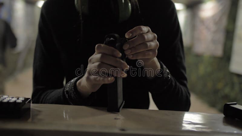 Girl loads ammo with pistol magazine stock photo