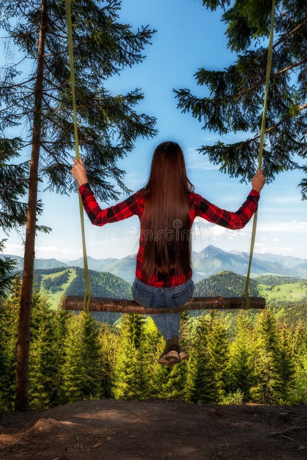 Girl with long hair on forest swing with beautiful mountain view