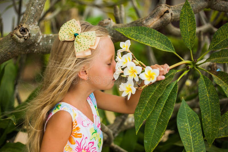 Girl with long hair smelling the flowers on the tree