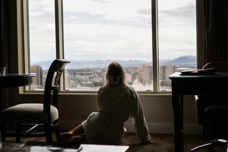 Girl Looking Out The Hotel Window Sitting On The FLoor Stock Photo