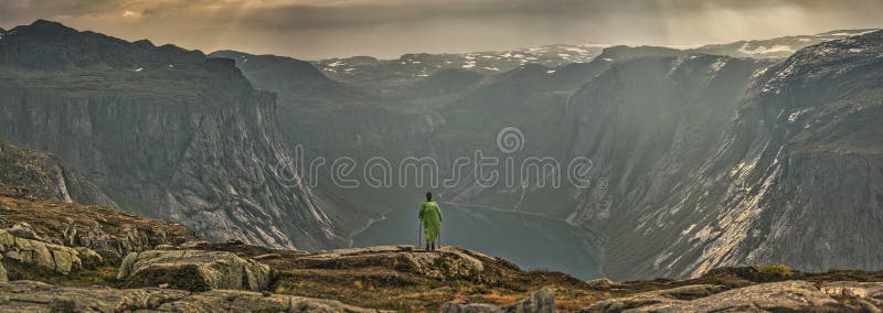 Girl looking at a picturesque view of the  fjord underneath close to Trolltunga