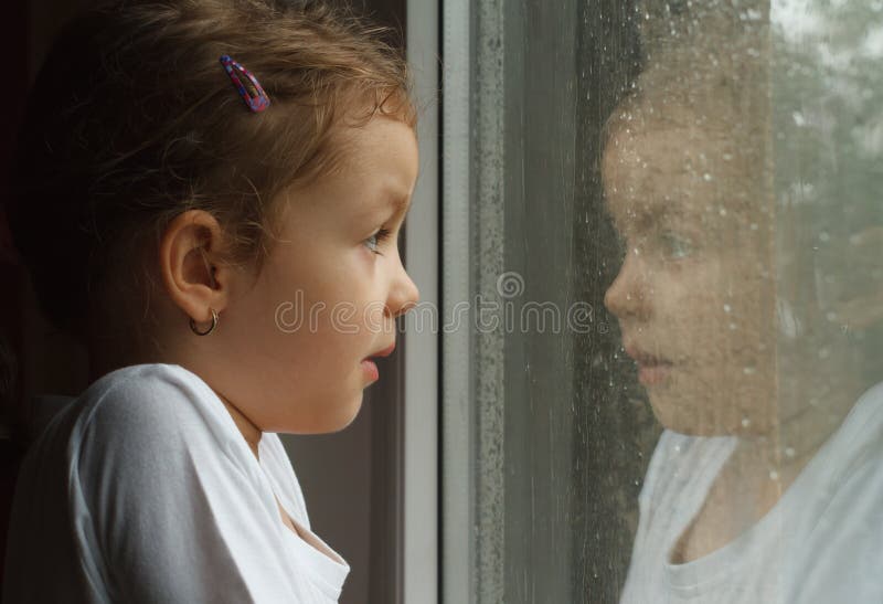 Girl looking at raindrops on the window