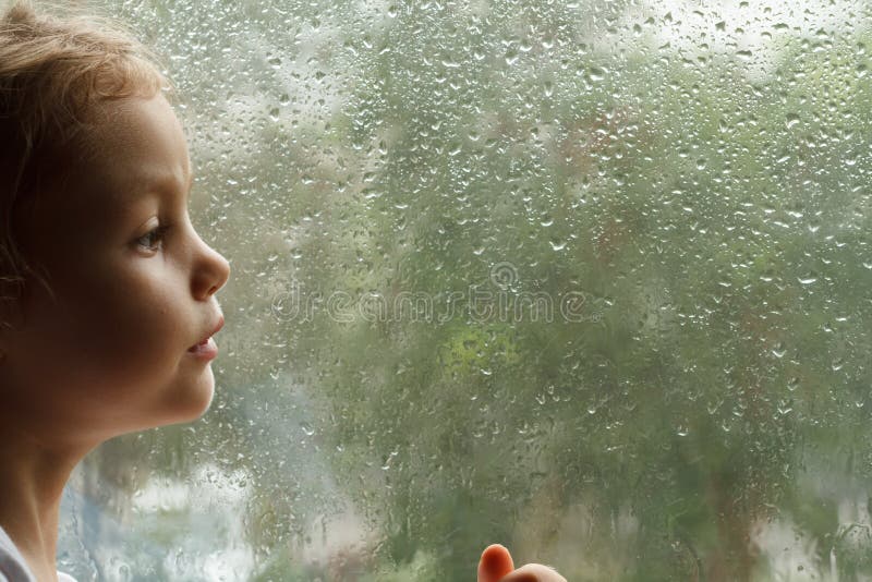 Girl looking at raindrops on the window