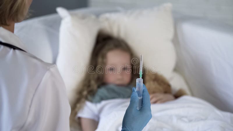 Girl looking at syringe in doctors hand with scared face, medical treatment royalty free stock photography Girl looking at syringe in doctors hand with scared face, medical treatment royalty free stock photography