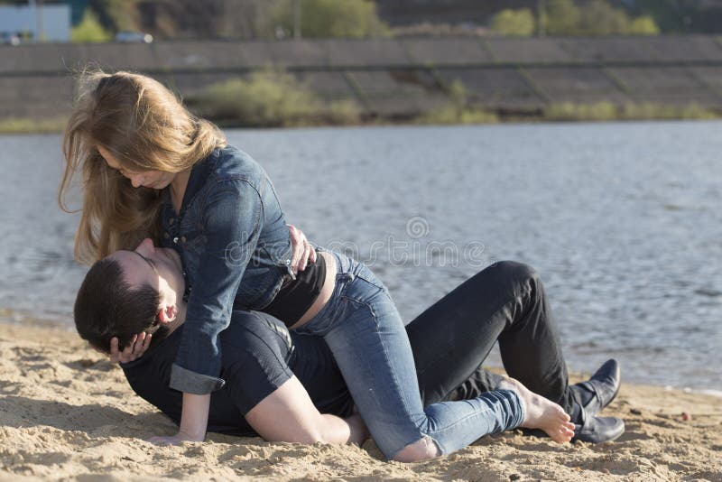 Girl lying down on the young man and looking to his face.