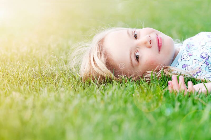 Una bambina, sorridente come si sdraia nell'erba fresca di primavera.