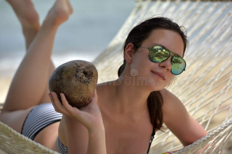 The girl is lying in a hammock with a coconut royalty free stock photos The girl is lying in a hammock with a coconut royalty free stock photos