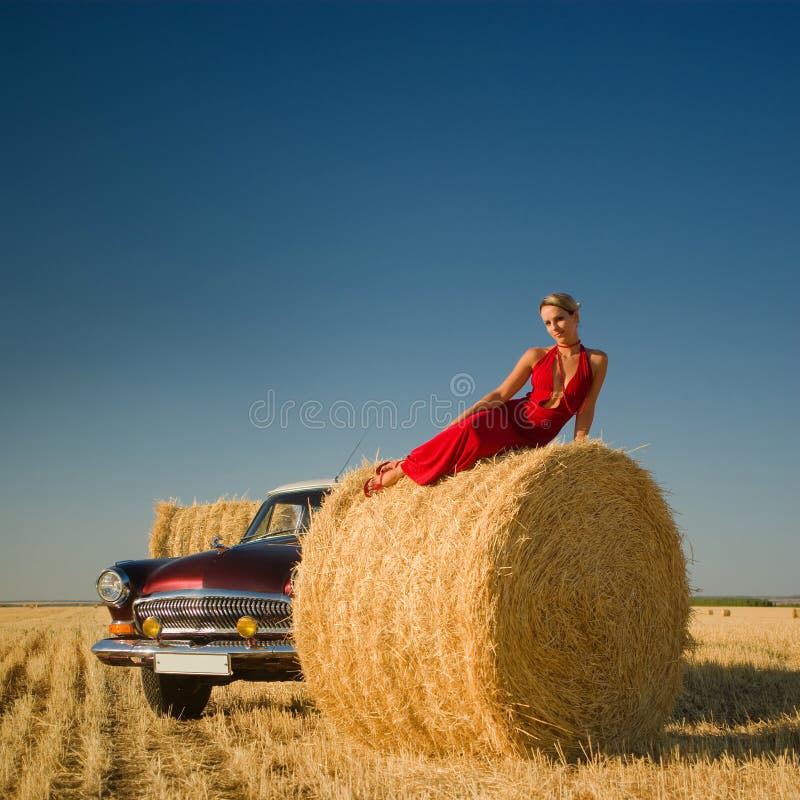 Girl lying on straw bale with retro car background