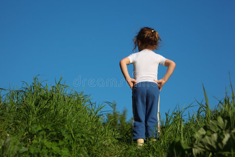 Girl makes gymnastic in grass, rear view