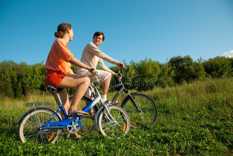 Girl and man go for drive on bicycles in sunny day