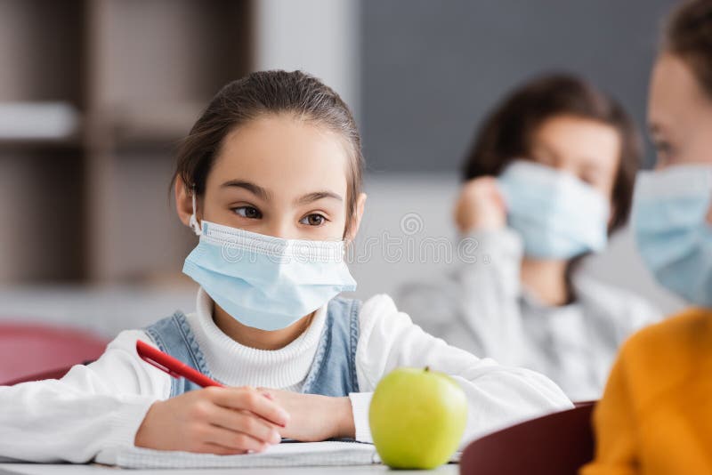 girl in medical mask holding pen