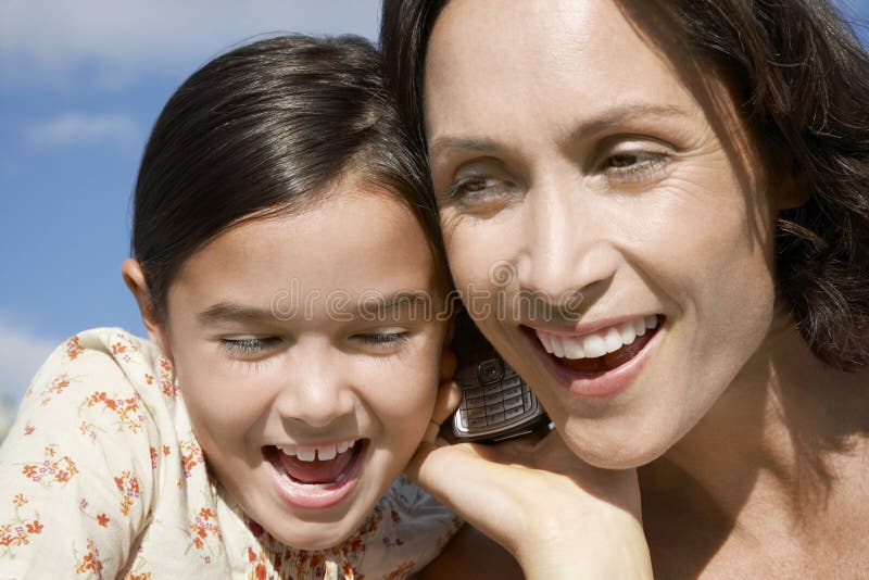 Girl And Mother Listening To Cell Phone