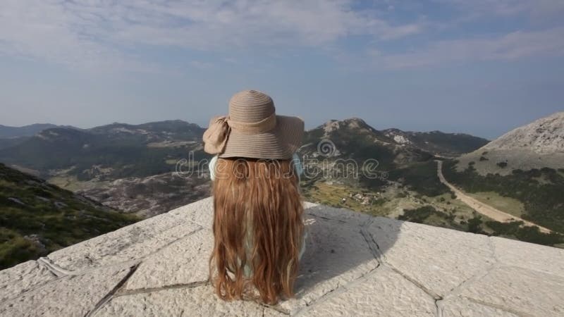 Girl on mountain top sit and admire the view