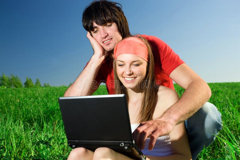 Girl with notebook and with boy on grass