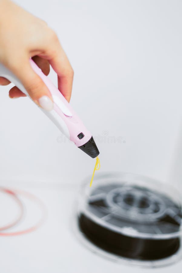 Girl with nude manicure draws 3d pen with a yellow plastic rod. 3d pen on a white background with a plastic coil. Girl with nude manicure draws 3d pen with a royalty free stock photography Girl with nude manicure draws 3d pen with a yellow plastic rod. 3d pen on a white background with a plastic coil. Girl with nude manicure draws 3d pen with a royalty free stock photography