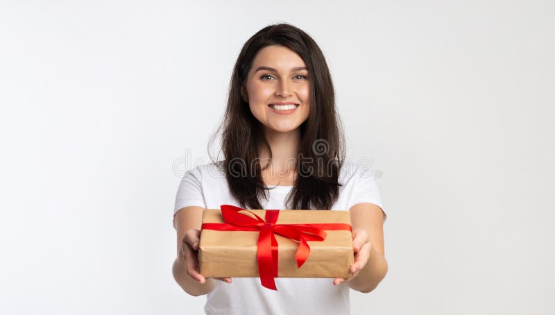 Girl Offering Wrapped Gift Box To Camera Standing, White Background royalty free stock image Girl Offering Wrapped Gift Box To Camera Standing, White Background royalty free stock image