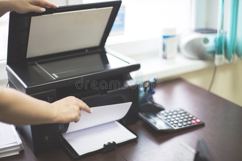 Girl in the office prints documents on a printer.