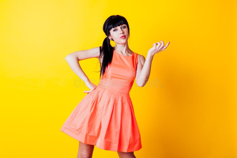 Girl in Orange Dress on a Yellow Background Hands Up Stock Photo ...