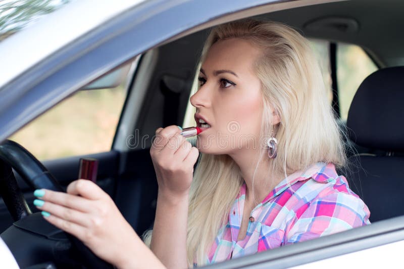 Girl paints her lips at the wheel the car