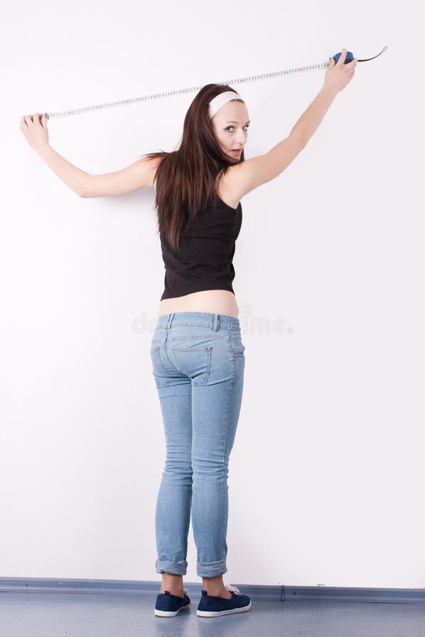 Girl measures a wall with a tape measure. Girl measures a wall with a tape measure