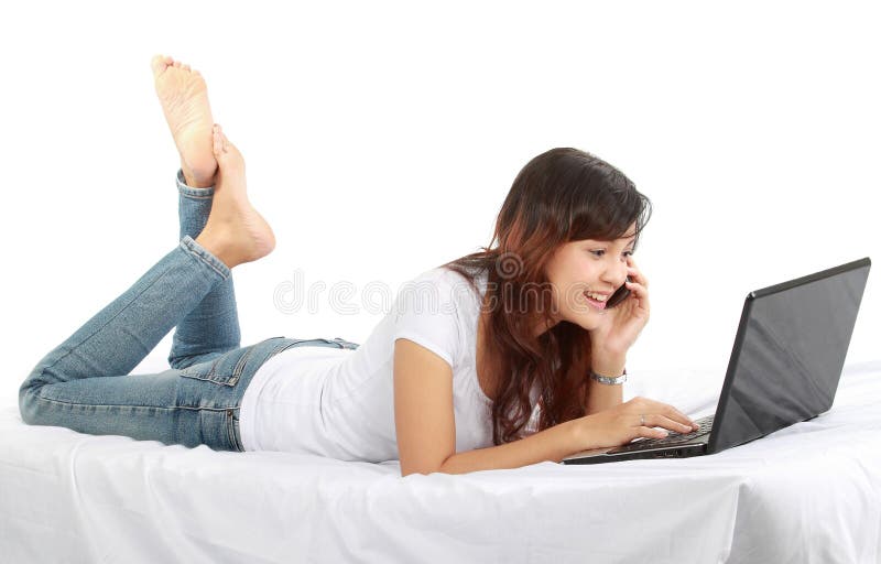 Girl on the phone on bed with laptop